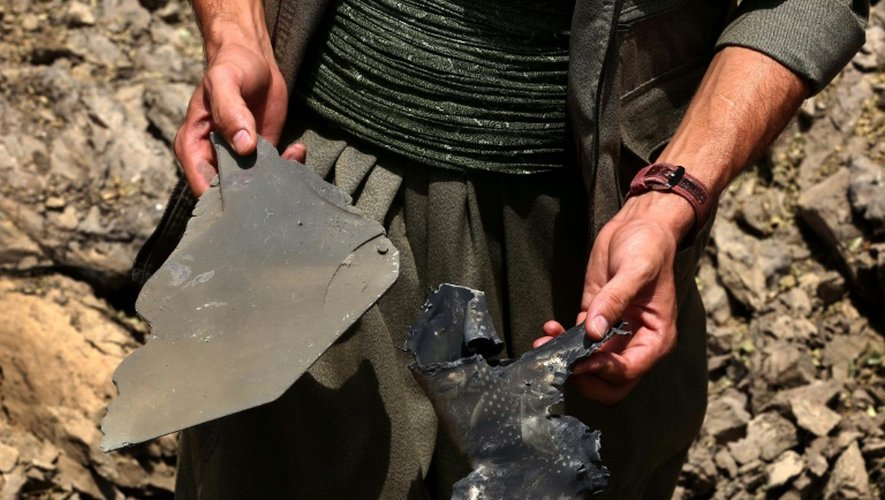 Un membre du PKK ramasse des fragments métalliques dans un cratère laissé par un bombardement de l'aviation turque, le 29 juillet 2015 aux monts Qandil, dans le nord de l'Irak