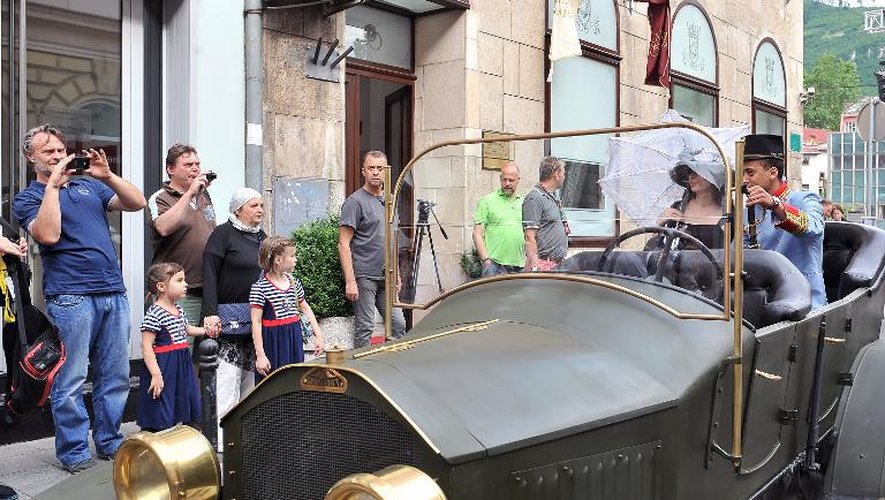 Des touristes posent le 27 juin 2014 à Sarajevo dans une réplique d'une voiture Graf et Stift garée à l'endroit où furent assassinés l'archiduc d'Autriche François Ferdinand et sa femme le 28 juin 1914