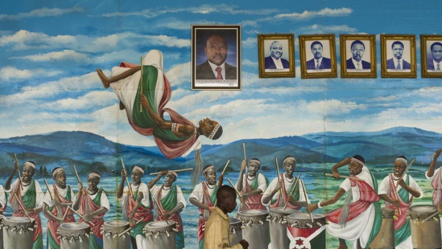 Un homme passe devant un mural  représentant des danseurs et des musiciens sous les portraits des présidents du Burundi jusqu'à présent, le 27 juillet 2015 à Bujumbura