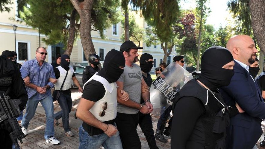 Des policiers emmènent Ilias Panagiotaros (d), Giannis Lagos (c) et Nikos Mihos (2e g), membres du parti néonazi grec Aube Dorée au tribunal d'Athènes, le 1er octobre 2013
