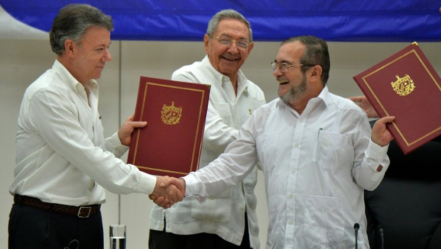 Le président colombien Juan Manuel Santos (g), le président cubain Raul Castro (c) et le chef suprême des Forces armées révolutionnaires de Colombie (Farc) Timoleon Jimenez (d) lors de la signature de l'accord de paix, le 23 juin 2016 à Cuba