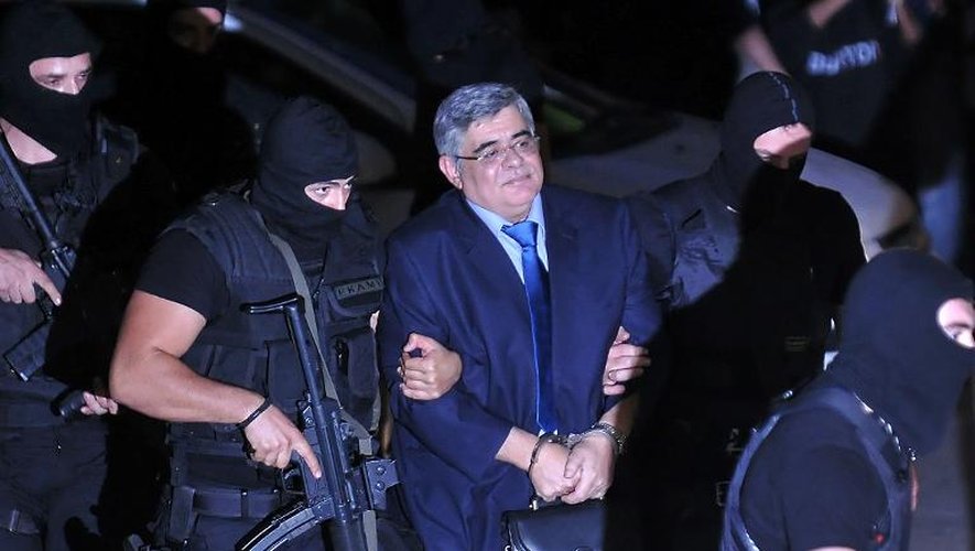 Nikos Michaloliakos entouré de policiers masqués le 2 octobre 2013 lors de son transfert au tribunal à Athènes