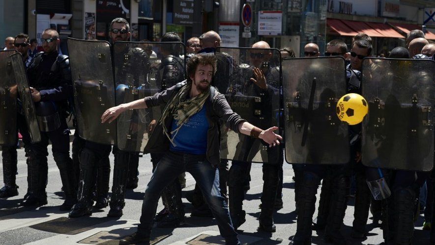 Un manifestant joue au ballon devant les policiers lors du défilé contre la loi travail à Lyon le 23 juin 2016
