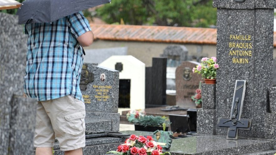 Un homme devant une tombe dont le crucifix a été renversé le 4 août 2015 dans le cimetière de Labry dans l'est de la France