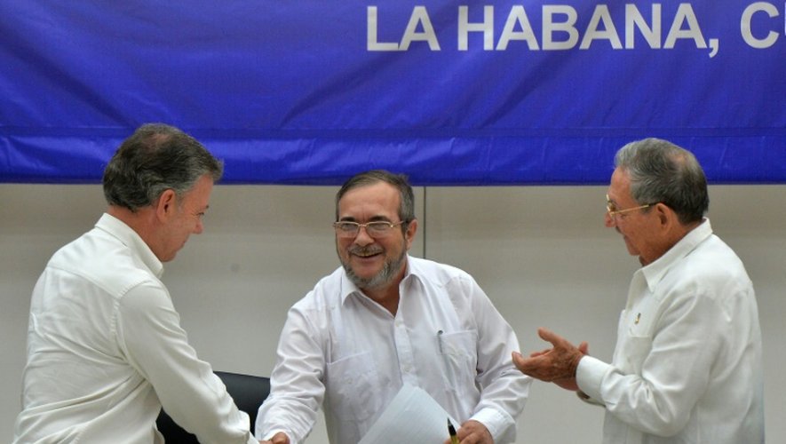 Le président colombien Juan Manuel Santos serre la main de Timoleon Jimenez, leader de la guerilla FARC, sous les applaudissements du président cubain Raul Castro, à la Havane le 23 juin 2016