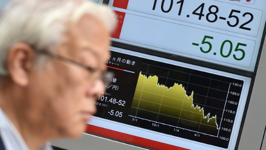 Un passant devant écran de changes d'une société d'investissement à Tokyo, le 24 juin 2016