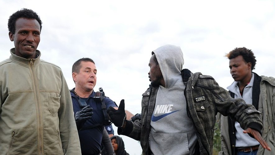 Un policier tente de stopper des migrants le 3 août 2015 à Coquelles près de Calais
