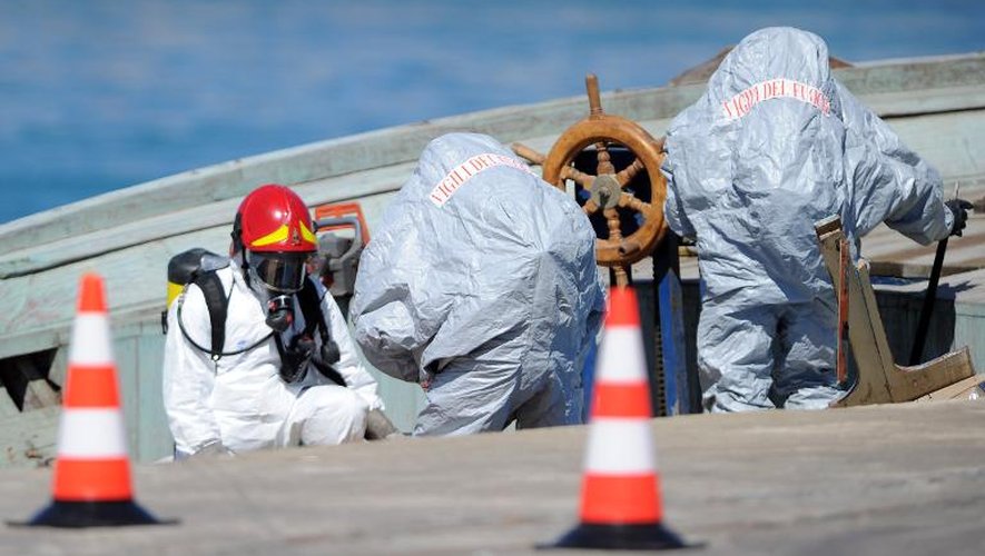 Des pompiers s'activent sur le bateau, le 1er juillet 2014 dans le port de Pozzallo en Sicile, où une trentaine de cadavres ont été découverts