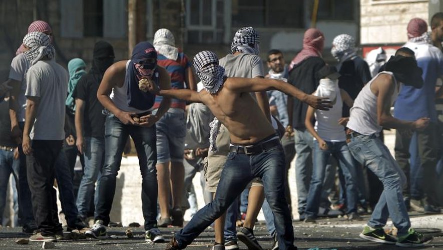 Des Palestiniens masqués lancent des pierres à l'encontre de forces de l'ordre israéliennes dans le quartier de Chouafat dans Jérusalem-Est, le 2 juillet 2014
