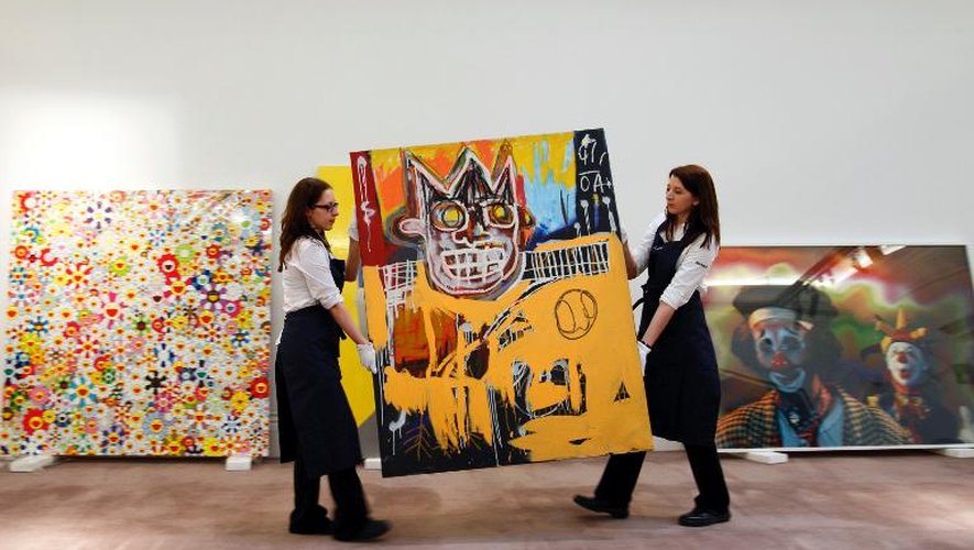 Deux employées de Sotheby's transportent le tableau de Jean-Michel Basquiat intitulé "Orange Sports Figure", le 1er février 2013 à Londres