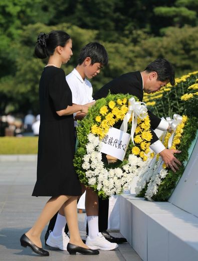 Des proches d'une des victimes du bombardement nucléaire déposent une gerbe le 6 août 2015 à Hiroshima, pour la cérémonie de commémoration du 70è anniversaire