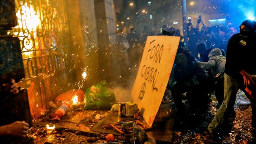 Des personnes masquées s'attaquent aux grilles de l'hôtel de ville de Rio, le 7 octobre 2013