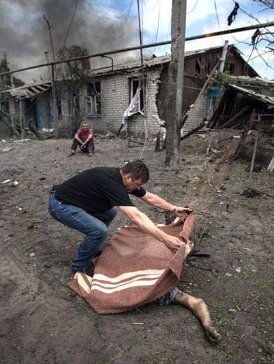 Un homme recouvre avec une couverture le corps d'une personne tuée dans le bombardement par l'aviation ukrainienne d'un village près de Lugansk, dans l'est de l'Ukraine, le 2 juillet 2014