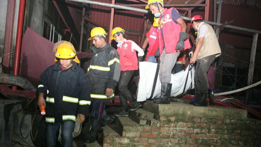 Le corps d'une victime emporté par les pompiers lors de l'incendie qui a fait 7 morts le 9 octobre 2013 dans une usine textile à Sripu dans la banlieue de Dacca