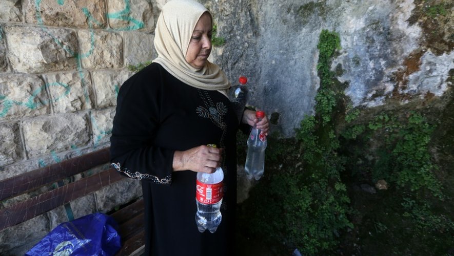 Une villageoise porte des bouteilles remplies d'eau de pluie, dans son village de Salfit (nord de la Cisjordanie), le 23 juin 2016