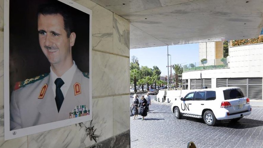 Un portrait du président syrien Bachar al-Assad sur un mur alors qu'un véhicule des inspecteurs de l'OIAC quitte un hôtel à Damas, le 9 octobre 2013