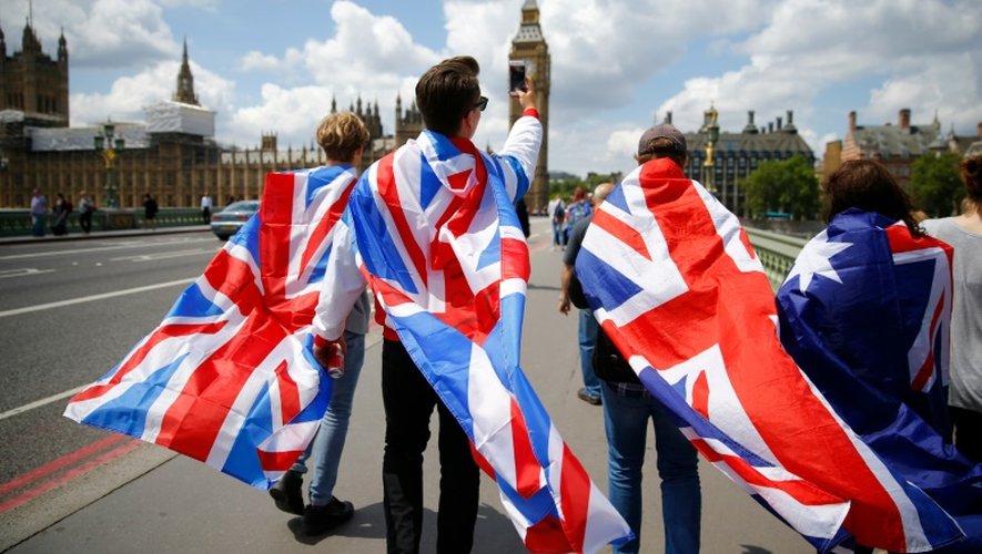 Des gens marchent sur le pont de Westminster enveloppés dans des drapeaux de l'Union Jack, le 26 juin 2016 à Londres