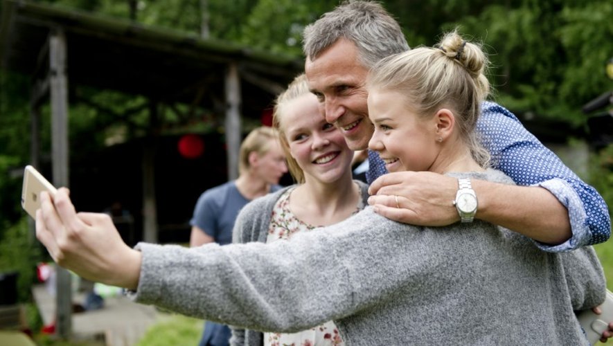 L'ancien Premier ministre travailliste, Jens Stoltenberg, chef du gouvernement au moment des faits, prend des photos avec deux jeunes filles lors du camp d'été des jeunes travaillistes sur l'île d'Utøya en Norvège, le 6 août 2015