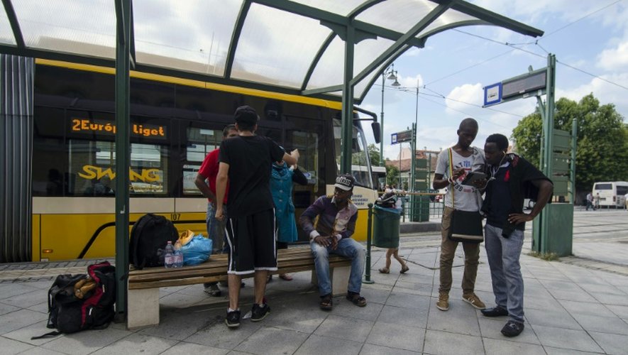 Un groupe de migrants attend un tram dans la ville hongroise de Szeged le 3 août 2015 après avoir franchi la frontière entre la Serbie et la Hongrie