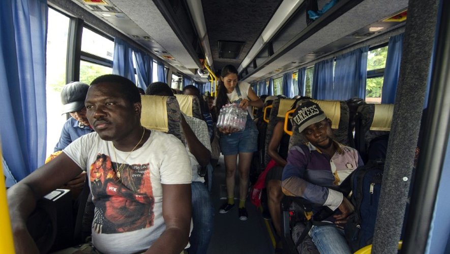 Une bénévole distribue des bouteilles d'eau aux migrants dans un autobus à Szeged (Hongrie), le 3 août 2015