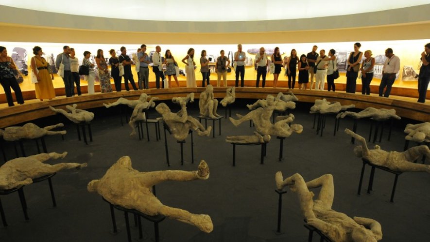 Des visiteurs regardent les moulages des corps des victimes de l'éruption de Pompéi, sur le site archéologique en cours de rénovation, le 5 août 2015