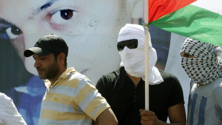 Un homme porte le drapeau palestinien derrière une photo géante de Mohammed Abu Khdeir, lors des funérailles de ce jeune palestinien, le 4 juillet 2014 à Jérusalem
