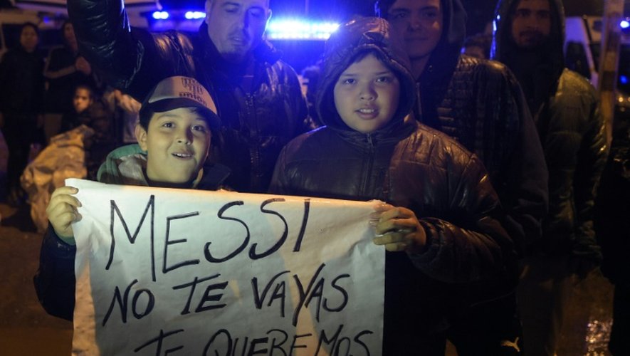 Des gens attendent l'arrivée de l'équipe d'Argentine avec un panneau disant "Messi, ne t'en vas pas, nous t'aimons" à Buenos Aires le 27 juin 2016