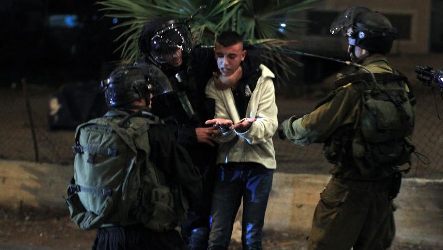Des soldats israéliens arrêtent un jeune palestinien, lors d'affrontements suite à un regain de violence, le 6 juillet 2014 dans un village de Cisjordanie