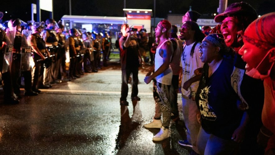 Un groupe de manifestants fait face à des policiers à Ferguson le 9 août 2015 dans la soirée, lors d'un rassemblement pour marquer le 1er anniversaire de la mort du jeune noir Michael Brown