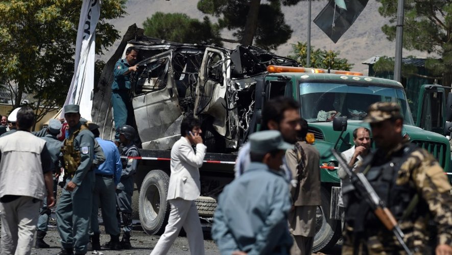 Des forces de sécurité afghanes contrôlent un véhicule détruit après une explosion près de l'entrée de l'aéroport de Kaboul, le 10 août 2015