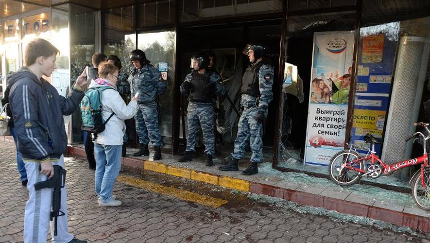 Des policiers anti-émeutes se tiennent devant une boutique dont l'entrée a été brisée, dans le sud de Moscou, le 13 octobre 2013