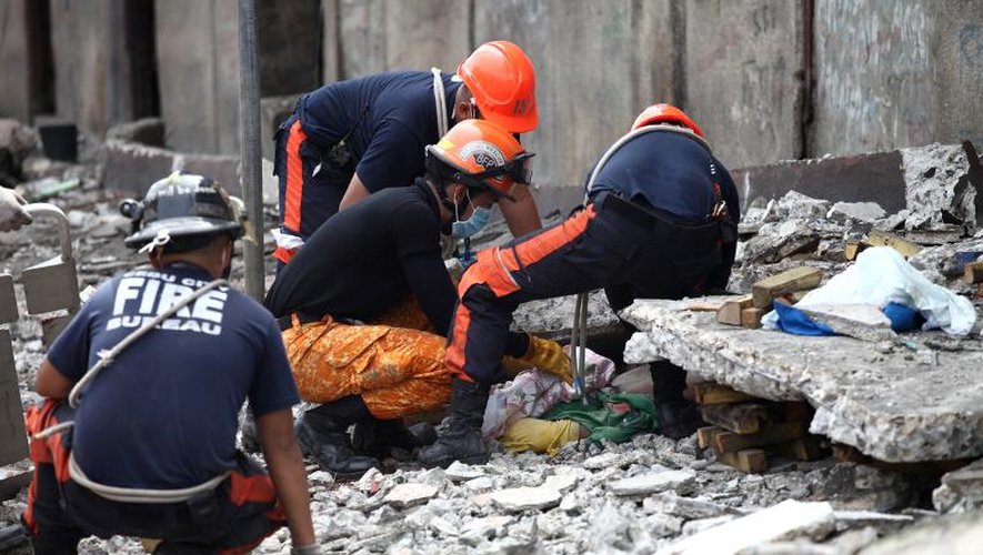 Des secouristes tentent de dégager une personne des décombres après un séisme à Cebu, le 15 octobre 2013 aux Philippines