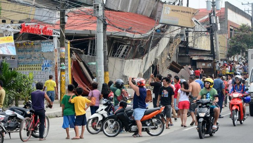 Des habitants de Cebu regardent des bâtiments effondrés après un violent séisme, le 15 octobre 2013 aux Philippines
