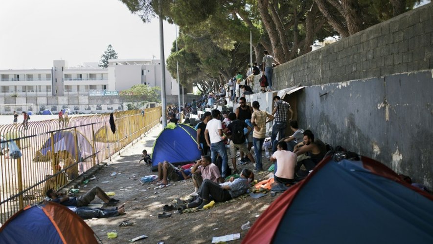 Des migrants attendent à l'extérieur du stade de l'île de Kos avant de pouvoir se faire enregistrer administrativement en Grèce, le 12 août 2015