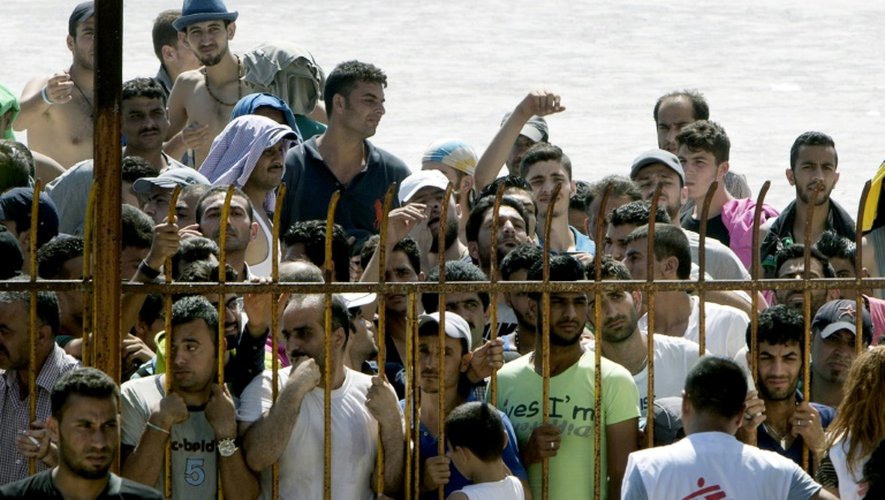 Des migrants attendent derrière une barrière pour entrer dans le stade de l'ïle de Koos pour se faire enregistrer administrativement, le 12 août 2015