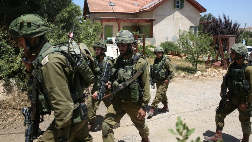 Des soldats israéliens à l'extérieur de la maison où une adolescente a été tuée le 30 juin 2016 à Kyriat Arba en Cisjordanie