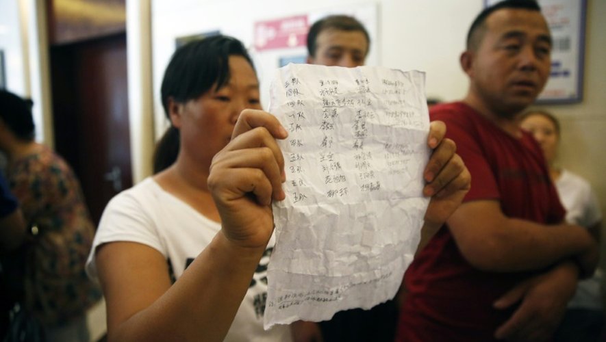 Une femme montre une liste avec les nom de pompiers disparus, après que les autorités ont empêché leurs familles d'accéder à une conférence de presse, le 15 août 2015 à Tianjin