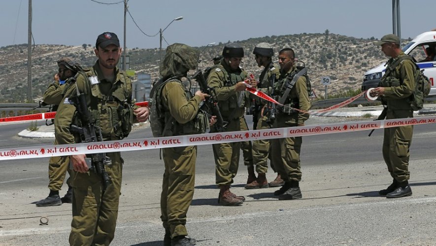 Des militaires israéliens délimitent un périmètre de sécurité autour de l'endroit où un jeune Palestinien a été blessé après avoir essayé de poignarder un soldat, le 15 août 2015 au village de Beit Ur, en Cisjordanie occupée