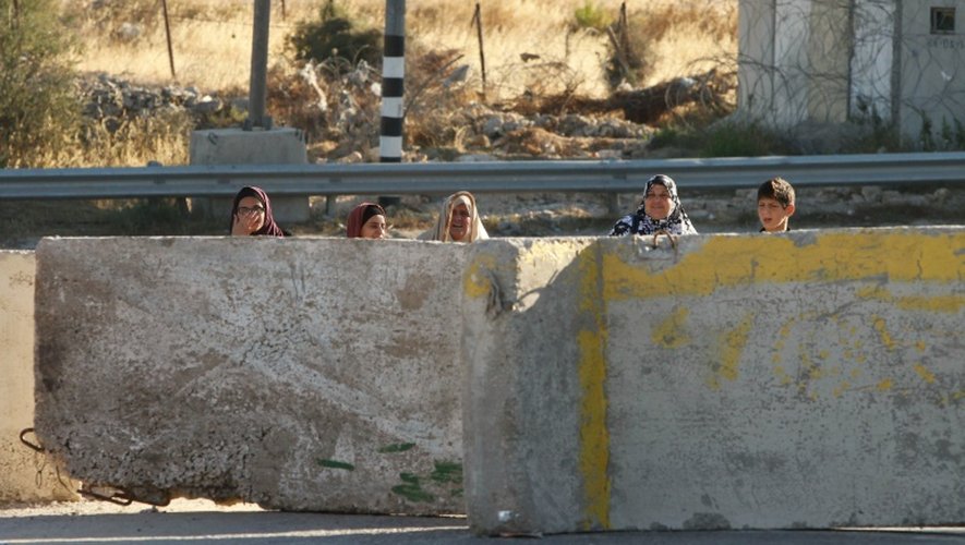 Des Palestiniens derrière des blocs de béton à l'entrée principale de Hébron, la plus grande ville de la Cisjordanie occcupée, le 2 juillet 2016