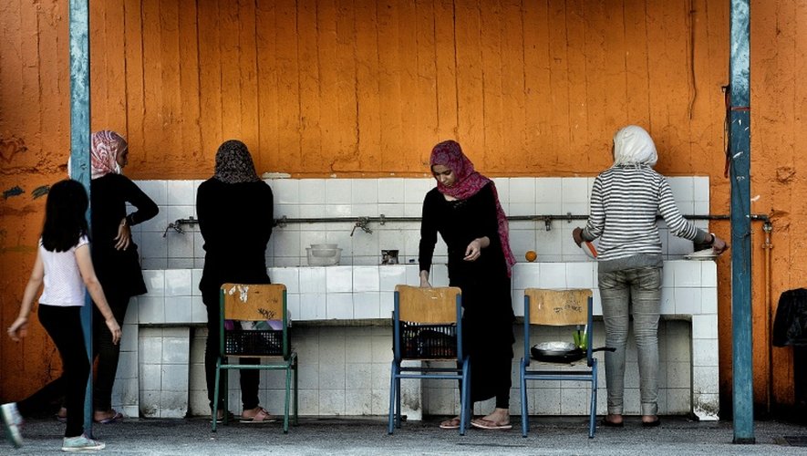 Des femmes font la vaisselle dans la cour d'une école fermée à Athènes squattée par des migrants, le 1er juillet 2016