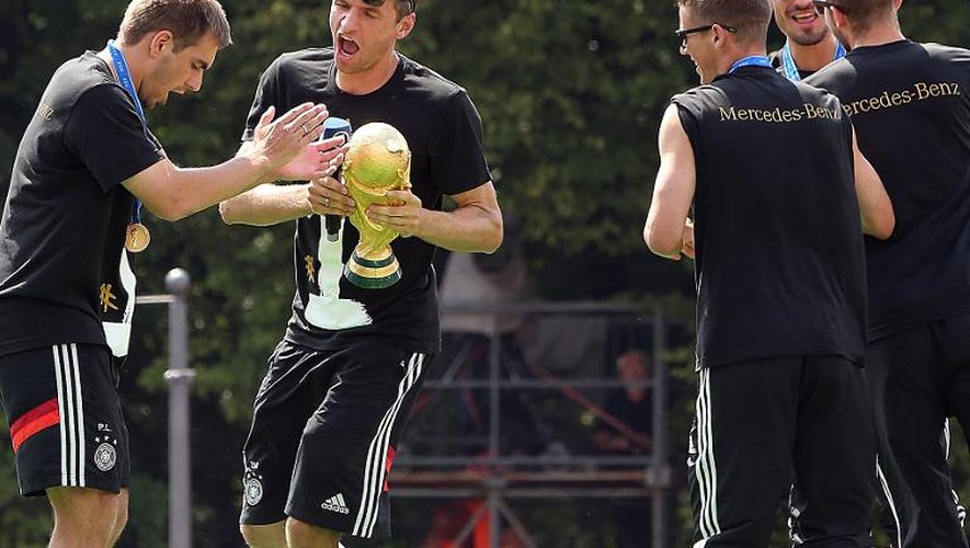 Le capitaine allemand Philipp Lahm et l'attaquant Thomas Müller s'amusent avec le trophée de la Coupe du Monde, Porte de Brandebourg à Berlin, le 15 juillet 2014