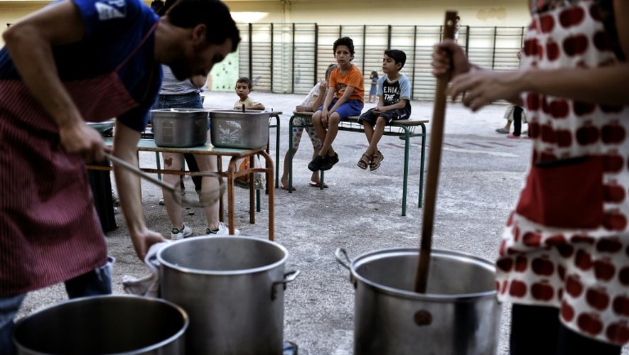 Des volontaires cuisinent dans la cour d'une école fermée à Athènes qui accueille des migrants, le 1er juillet 2016