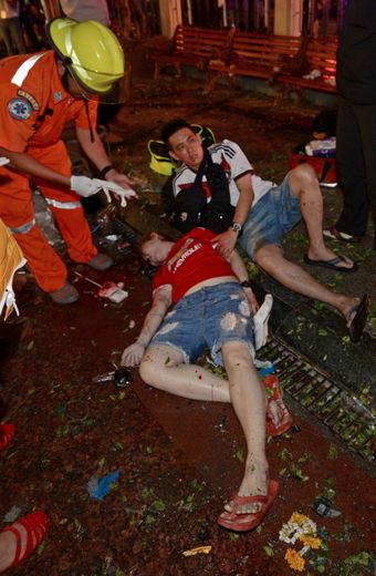 Un sauveteur thaïlandais près de deux personnes blessées après l'explosion d'un bombe à Bangkok qui a fait au moins dix morts, le 17 août 2015