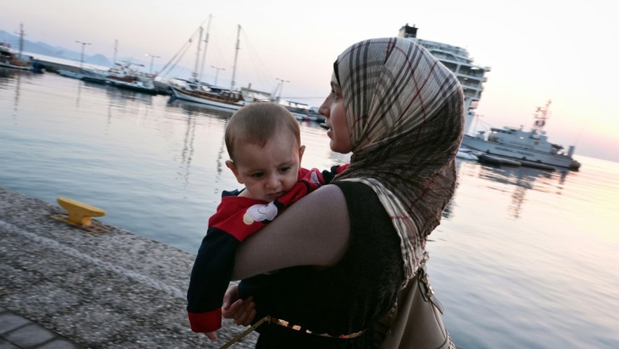 Une syrienne et son enfant attendent d'être enregistrés administrativement dans le port de l'île de kjos en Grèce, le 17 août 2015