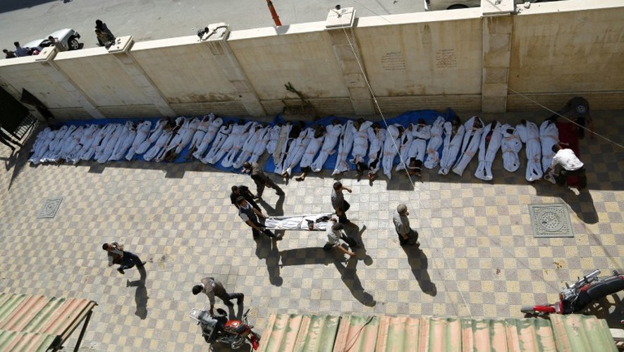 Des secouristes s'affairent à proximité des cadavres enveloppés dans des linceuls des victimes des frappes aériennes menées par des forces gouvernementales à Douma le 16 août 2015