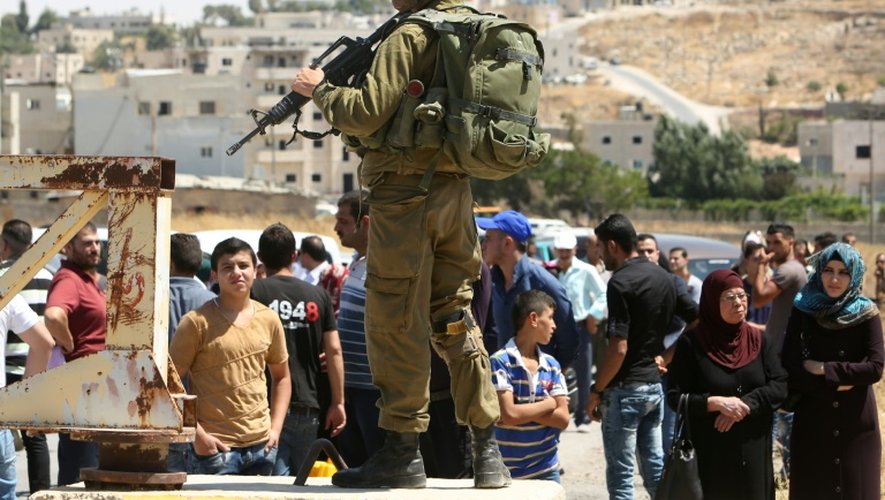 Des Palestiniens attendent, le 3 juillet 2016, à un point de contrôle au sud d'Hébron, mis en place par Israël en réponse à une série d'attaques palestiniennes