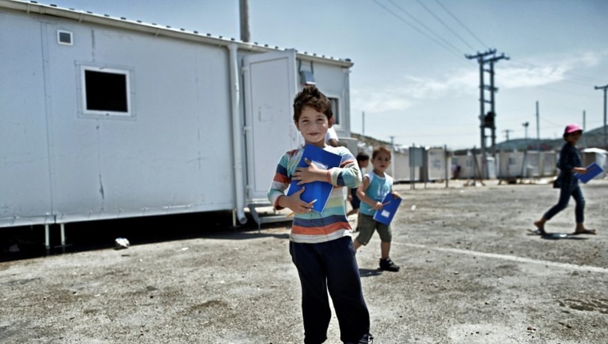 Un jeune garçon devant un conteneur reconverti en salle de classe, le 24 juin 2016 dans le camp de réfugiés de Skaramangs (sud de Athènes)