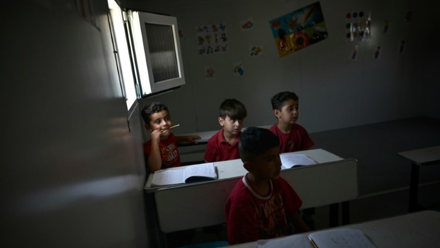 Des jeunes enfants suivent une leçon d'anglais dans une classe installée dans un conteneur dans le camp de réfugiés de Skaramangas (sud d'Athènes), le 24 juin 2016