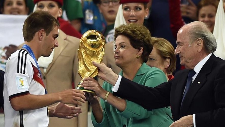 Le capitaine de l'Allemagne Philipp Lahm reçoit la Coupe du monde des mains de la présidente brésilienne Dilma Roussef, le 13 juillet 2014 à Rio de Janeiro