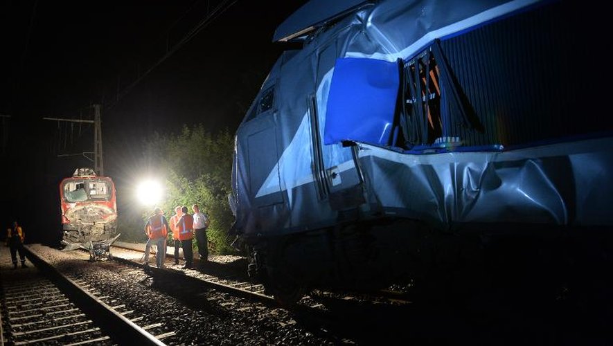 Des employés de la SNCF et des pompiers examinent un train à Denguin après une collision entre un TGV et un TER le 17 juillet 2014